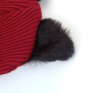 Close-up of deep red knit texture and black plush cat ear detail on a winter beanie