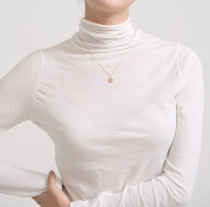 Detailed close-up of a minimalist gold necklace with a hammered irregular round pendant