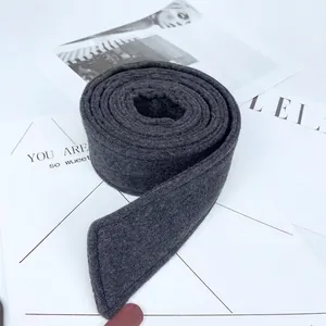 Dark grey wool coat belt accessory with fine stitching, rolled for a modern display