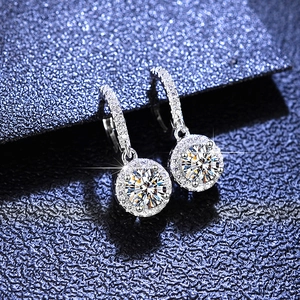 Detailed view of silver halo moissanite earrings with sparkling pavé accents on blue background