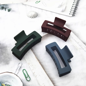 Three matte large hair claws in dark green, navy blue and burgundy on a desk