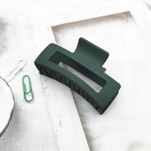Detailed view of matte dark green hair claw clip with rectangular cutout on white frame