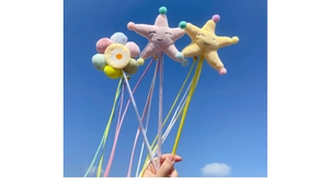 Detail of plush sunflower and star cat wands with colorful ribbons against a blue sky