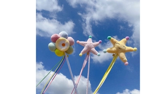 Detail of plush starfish and flower cat wand toys with colorful ribbons against blue sky
