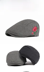Détail de broderie de roses rouges sur un béret en laine gris anthracite pour l'hiver