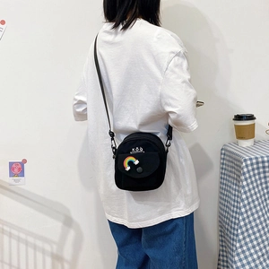 Minimalist black canvas crossbody bag for women with rainbow cloud embroidery on a white background