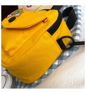 Detail of yellow canvas crossbody bag with rainbow badge on blue checkered fabric