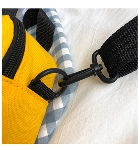 Close-up of yellow canvas bag with black plastic D-ring hook and nylon shoulder strap