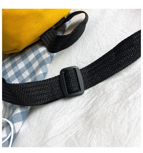 Close-up of adjustable black nylon strap and buckle on a yellow canvas crossbody bag