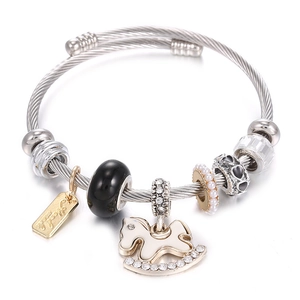 Detailed close-up of woven steel bracelet with enamel rocking horse and heart charms