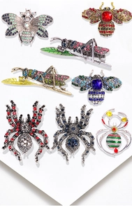 Detailed flat lay of insect-themed crystal brooches featuring bee, grasshopper, and spider