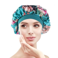 Detail of teal satin sleep bonnet featuring pink floral patterns and a wide elastic band