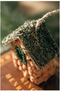 Makroaufnahme von rustikalem Vogelhaus-Anhänger aus Holz mit Moosdach und Juteseilschlaufe
