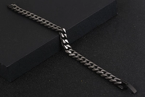 Détail d'un bracelet gourmette noir mat sur un présentoir géométrique minimaliste