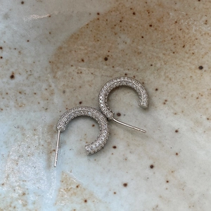 Macro shot of silver C-shaped pave earrings with high-grade crystals on ceramic
