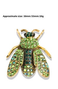 Detailed close-up of green crystal bee brooch with golden alloy and size markings