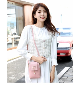 Detailed view of pink woven crossbody phone bag with cat-ear ring and pearl tassels