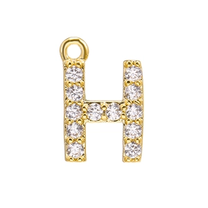 Macro detail of gold-plated capital letter H pendant encrusted with sparkling zircons