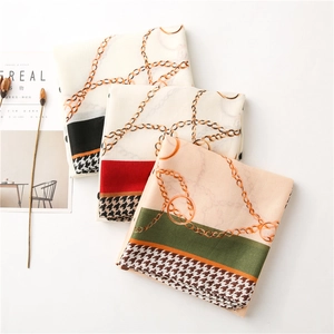 Dettaglio flat lay di tre sciarpe stampate con motivi a catena e trama pied-de-poule