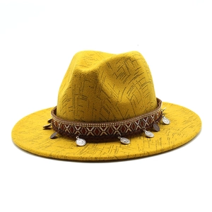 Close-up of yellow wool fedora featuring ethnic embroidery and hanging silver metal coins
