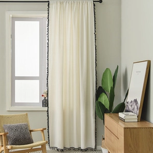 Detail of minimalist cream linen curtain with elegant black pompom fringe trim for decor