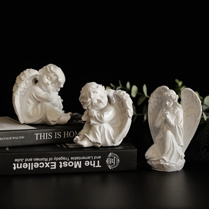 Trois figurines d'ange en résine blanche texture mate sur un fond noir profond