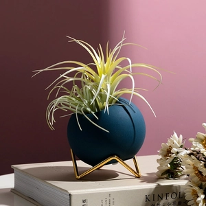 Modern matte blue spherical flower vase with a gold tripod stand for home decoration