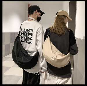 Detailed back view of black and beige nylon crescent crossbody bags on male and female models