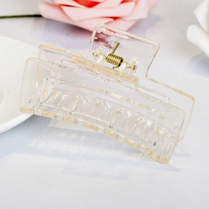 Macro shot of a transparent square hair claw clip with a durable gold metal spring detail