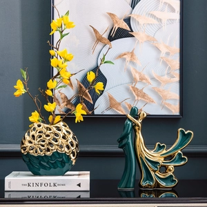 Moderne keramische vogels met gouden vaas en bloemen voor decoratie van woonkamerplanken