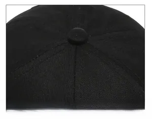 Close-up of the reinforced stitching and fabric button on top of a black baseball cap