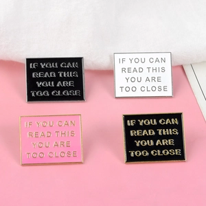Detail shot of four enamel pins with text If You Can Read This You Are Too Close