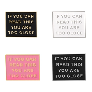 Macro display of four color variants for the enamel warning sign brooches in a 2x2 grid