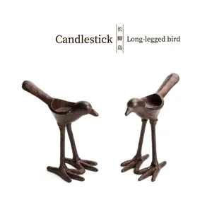 Vintage iron bird-shaped candlesticks with rustic brown finish on white background