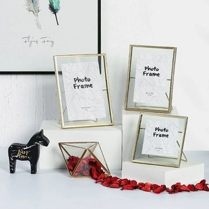 Nordic geometric metal glass photo frames and matching glass vase on a white stand