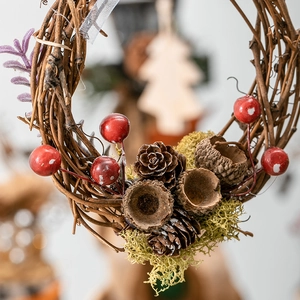 Christmas wreath with red berries, pine cones and green moss on natural brown vine frame