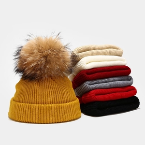 Chic knitted beanies with large fluffy pom poms in various warm autumn colors