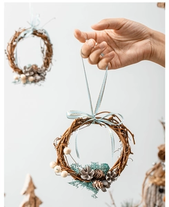 Close-up of a handmade rattan Christmas wreath with pine cones and red berries hanging