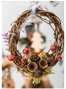 Detail of a handmade grapevine wreath with red berries, pinecones, and white mesh bow