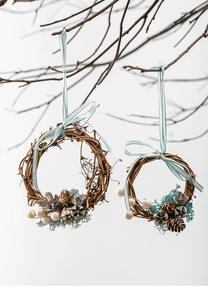 Detail of handmade Christmas mini wreaths with natural pine cones and light blue ribbons