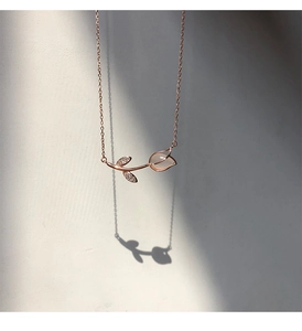 Artistic shadow play of a rose gold tulip necklace with opal pendant on a white background