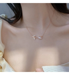 Close-up of rose gold tulip pendant necklace with cat eye stone worn by a model