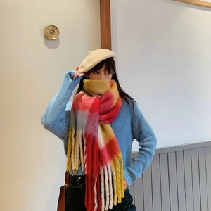 Close-up of thick braided rainbow plaid scarf with colorful fringes and soft texture