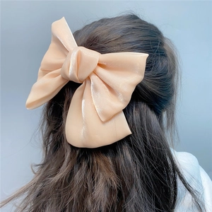 Detail view of a large champagne organza bow hair clip worn as a half-up hair accessory