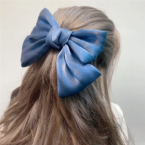 Large satin blue organza bow hair clip shown from the back on long hair for a sweet look