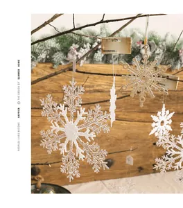 Detail showing white and gold glitter snowflake ornaments hanging on festive branches