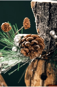 Close-up of pine cones, green needles, and silver balls on a rustic wooden base decoration