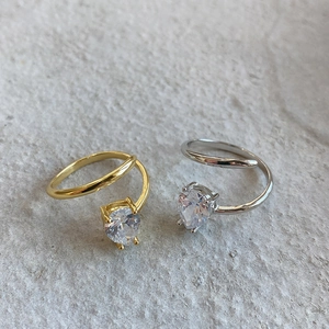 Detailed view of silver and gold open rings with pear-cut zircon in claw setting