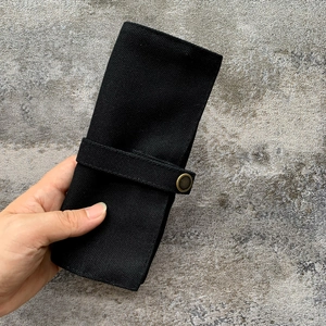 Zwarte canvas horlogeband opslag rol tas organizer met drukknop detail voor slimme horloges.