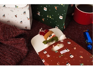 Close-up of Christmas gift bags featuring a cute knitted snowman inside a red paper bag